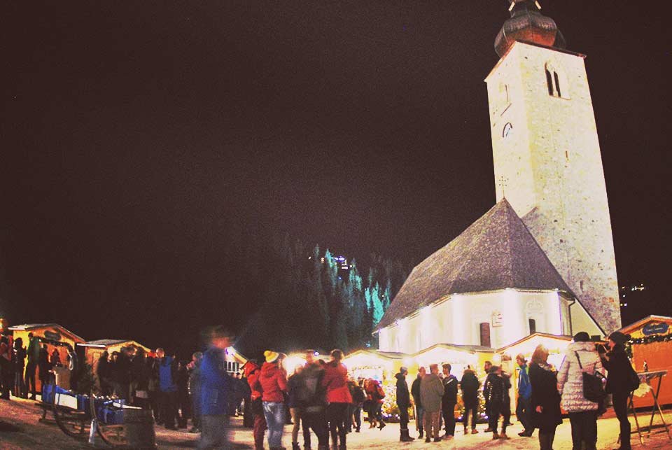 People standing in a Christmas market beneath a church