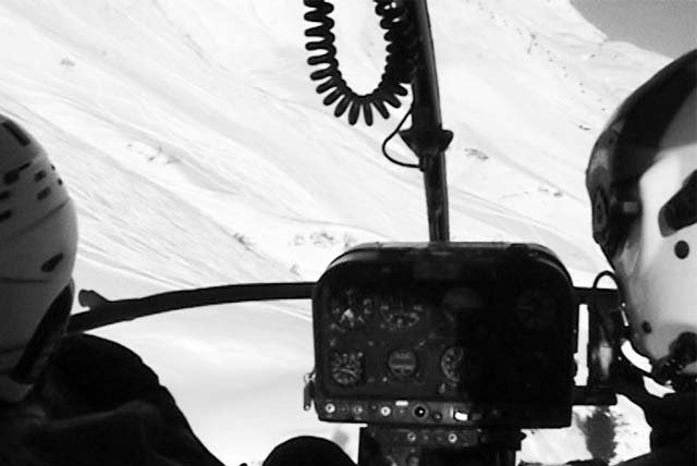 View from a helicopter cockpit over snowy mountains