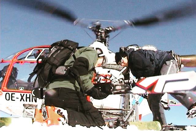 Skiers unloading skis from a helicopter on a snowy mountain
