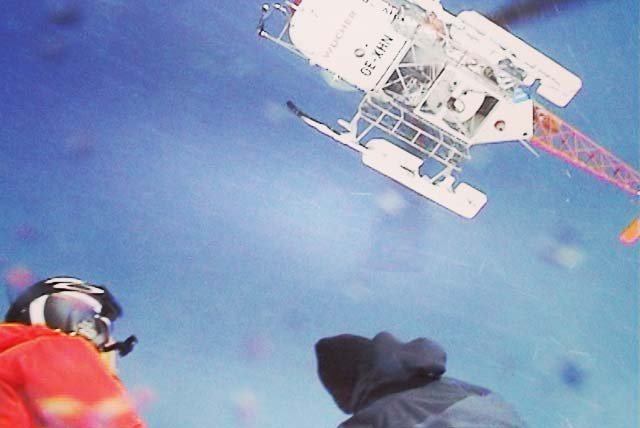 Helicopter flying off above skiers