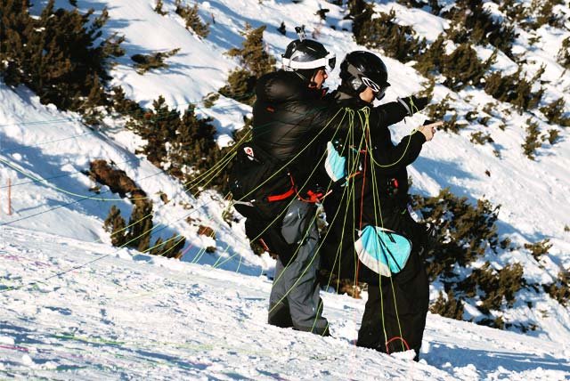 Paraglider pilot and passenger checking the cords