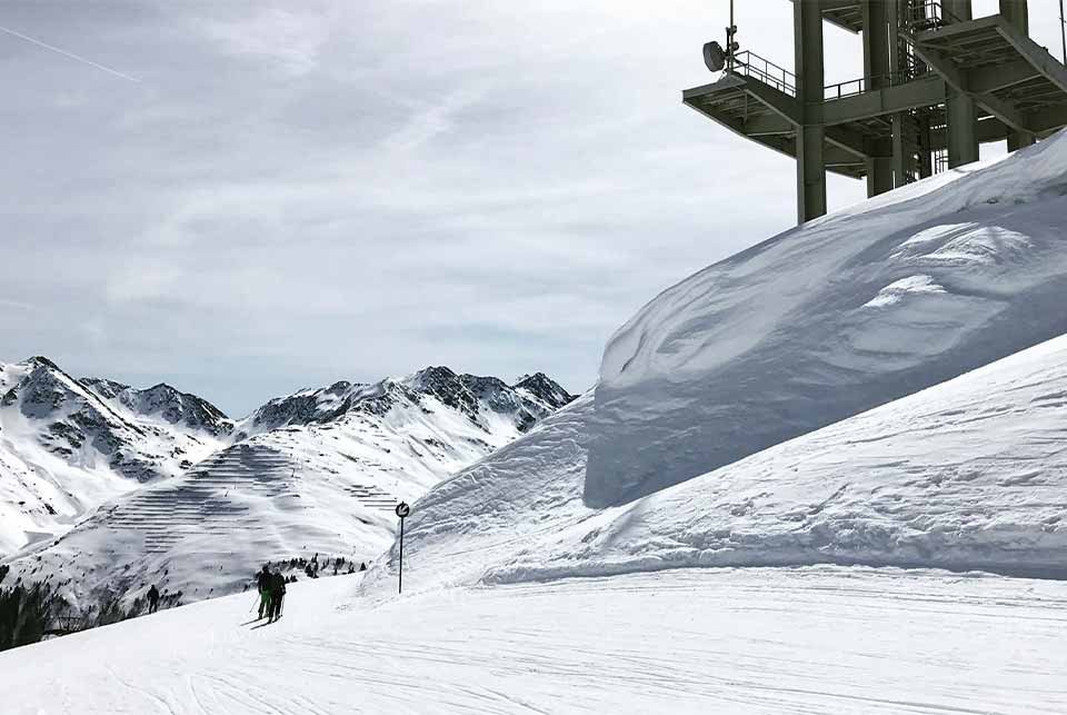 Skiers riding a ski piste next to a huge wall of snow
